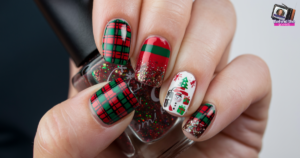 Close-up of a hand with festive nail art. Nails feature red, green plaid patterns, glitter, and Christmas-themed designs including a Santa face, tree, and gift on a white background. The thumb holds a black nail polish bottle.