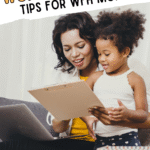 A woman sits on a couch working on a laptop with a clipboard, while a young girl stands beside her looking at the clipboard. Text above reads Work-Life Balance: Tips for WFH Moms.